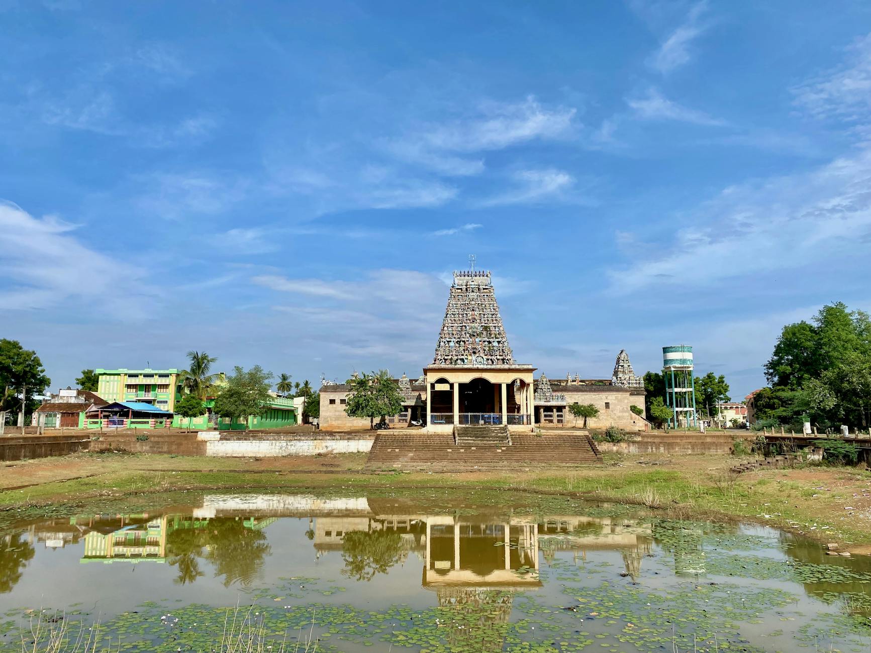 small lake in a park with a south indian temple in the background