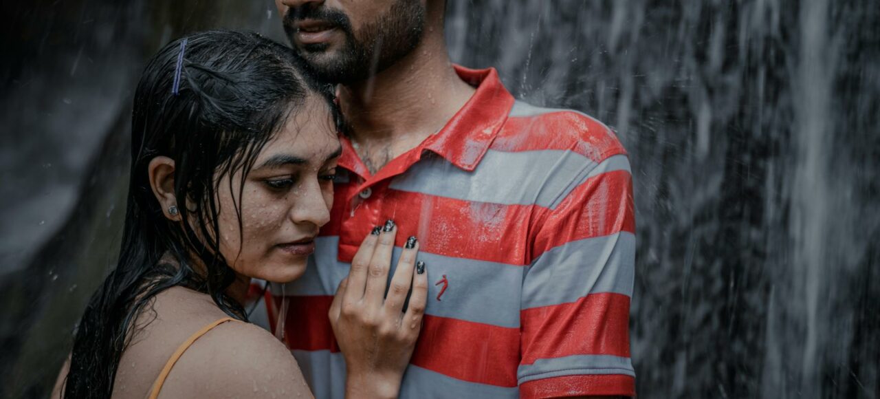 wet couple standing under waterfall