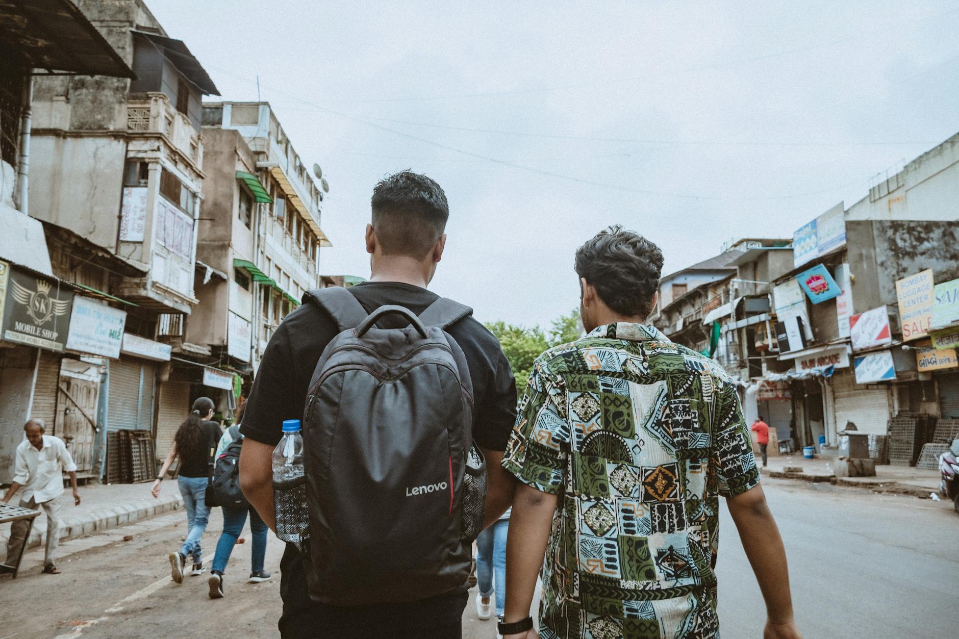 two men walking down a street with backpacks