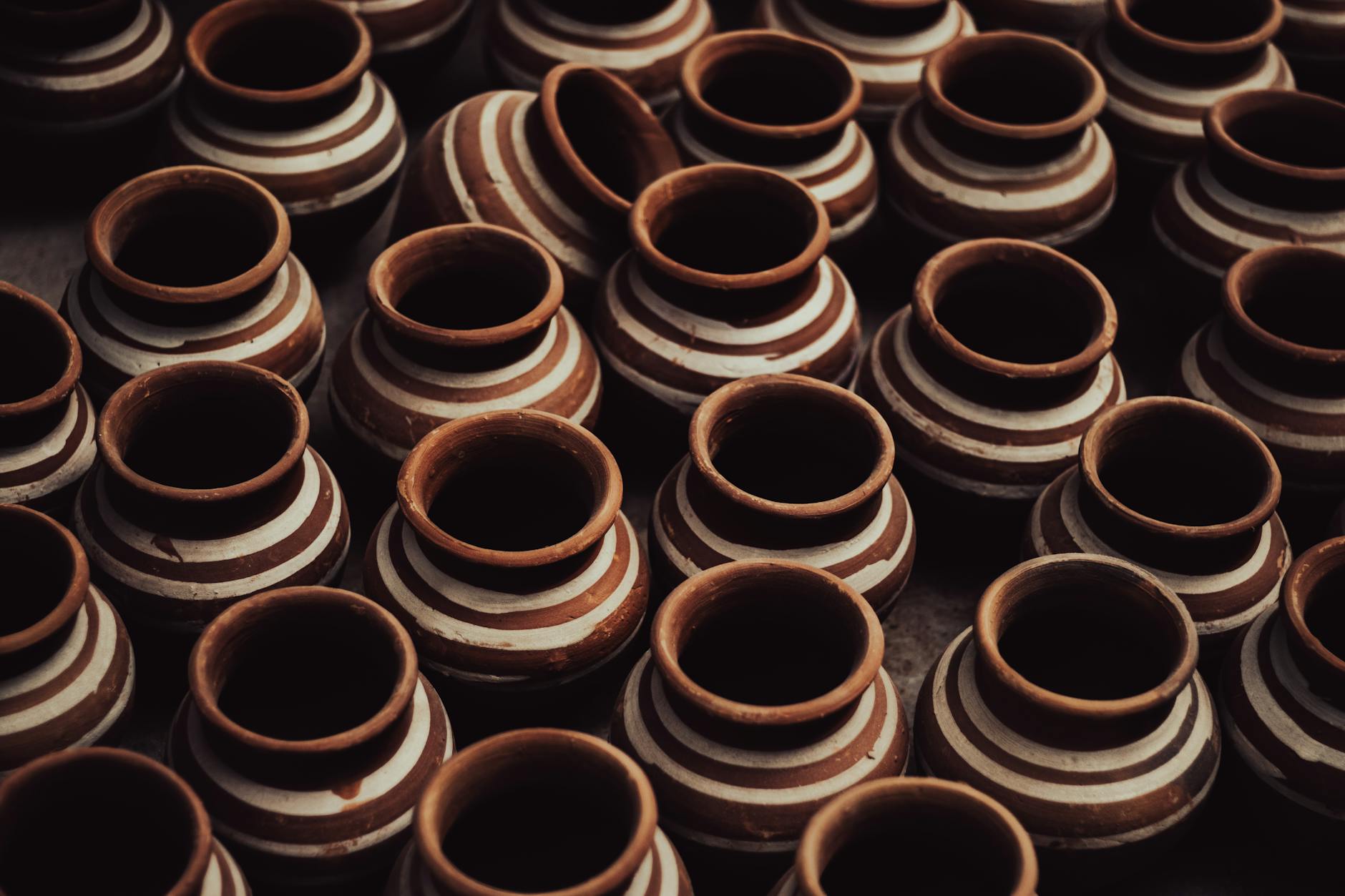 a group of brown clay pots with white stripes
