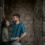 laughing couple leaning on stone wall