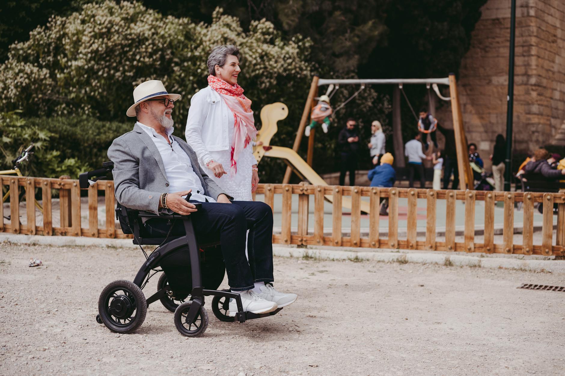 man using a mobility aid passing by a playground