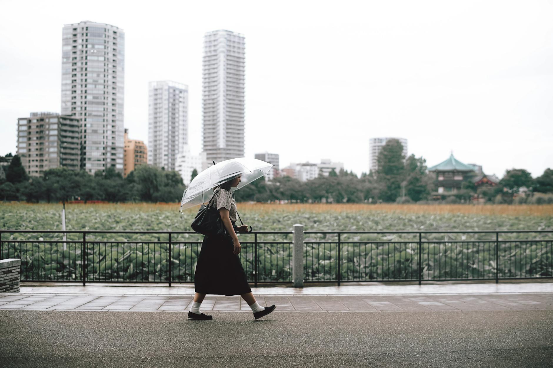 girl walking on sidewalk with an umbrella